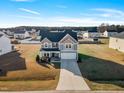 Wide aerial view of a two-story home with gray siding, a two-car garage, and a large, well-kept lawn at 109 Perignon Dr, Princeton, NC 27569