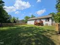Large lawn in backyard with a wooden deck attached to the home, and a full wooden fence surrounding the property at 1212 E Middleton Dr, Creedmoor, NC 27522
