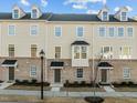 Charming townhomes with a combination of tan siding and brick exteriors and black door and roof accents at 1414 Excelsior Grand Ave, Durham, NC 27713