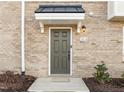 Close-up of the brick townhome's front door, featuring a small overhang and house number 1414 at 1414 Excelsior Grand Ave, Durham, NC 27713