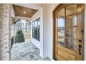 Close-up of the front door, featuring glass panels, wood trim, and a covered porch with stone flooring at 240 Seaforth Landing Dr, Pittsboro, NC 27312