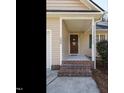 A close up of the front porch features brick steps and a beautiful wreath on the front door at 504 Forrest Dr, Sanford, NC 27330