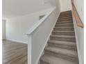 Carpeted staircase leads to the second floor with landing and wooden handrail at 556 Winding Creek Dr Dr, Lillington, NC 27546
