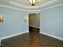 Cozy living room with hardwood floors, tray ceiling, decorative sconces and fresh paint at 905 Maynard Creek Ct, Cary, NC 27513