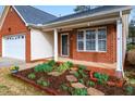 Home's entryway and front porch area, featuring a brick facade and a landscaped flower bed at 109 Kudrow Ln, Morrisville, NC 27560