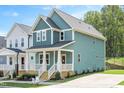 An angled view of a blue two-story home showcasing its well-maintained lawn and modern architectural design at 120 Weavers Grove Dr, Chapel Hill, NC 27514