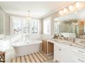 Bright bathroom with a freestanding tub beneath shuttered windows, and a vanity with stone countertop and elegant chandelier at 2511 Pineway Dr, Burlington, NC 27215
