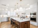 Bright, open kitchen features white cabinets, herringbone floors, a large island, and stainless steel appliances at 2511 Pineway Dr, Burlington, NC 27215