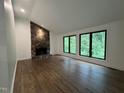 Inviting living room boasts a stone fireplace, hardwood floors, and large windows with picturesque views at 3412 Rock Creek Dr, Raleigh, NC 27609