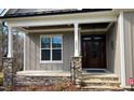Inviting front porch with stone accents and a stylish wooden door, enhancing curb appeal at 3805 Watermark Dr, Franklinton, NC 27525