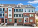 Three-story brick townhouses with multi-tone exteriors, black shutters and dormer windows under a blue sky at 507 Gateway Townes Blvd, Wake Forest, NC 27587