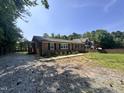 Inviting brick home with a covered porch and a gravel driveway leading to a spacious yard at 7103 Big Horn Dr, Hillsborough, NC 27278