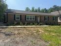 Classic brick home featuring black shutters, a simple walkway, and fresh landscaping at 7103 Big Horn Dr, Hillsborough, NC 27278