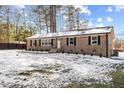 Single-story brick home featuring a classic design with black shutters and snowy yard at 7103 Big Horn Dr, Hillsborough, NC 27278