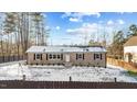 Welcoming brick home with black shutters and a snow-covered yard at 7103 Big Horn Dr, Hillsborough, NC 27278