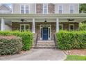 Inviting front porch with stone pillars, a dark blue front door, and neatly trimmed hedges at 7400 Bleasdale Ct, Apex, NC 27539