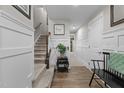 Inviting hallway featuring wainscoting, hardwood floors, and a staircase to upper level at 905 Arnold Place Dr, Fuquay Varina, NC 27526