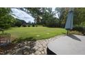 Lush backyard with manicured lawn, mature trees, and a stone patio with outdoor seating, ideal for relaxation at 2490 Earpsboro Rd, Zebulon, NC 27597