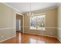 Elegant dining room with hardwood floors, chandelier, and large windows, perfect for entertaining at 104 Riley Oaks Ln, Apex, NC 27539