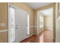 Bright entryway featuring a window-lined front door and hardwood floors, with a glimpse of a sunlit room at 104 Riley Oaks Ln, Apex, NC 27539