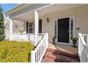 Welcoming front porch with white railings, brick steps, and a black front door flanked by potted plants at 104 Riley Oaks Ln, Apex, NC 27539
