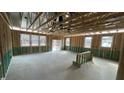 Unfinished living room featuring exposed beams, natural light from three windows, and a sliding glass door at 178 Gobbler Dr, Smithfield, NC 27577