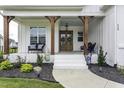 Inviting front porch with comfortable seating, wood columns, and a beautifully decorated double-door entrance at 113 Nate Court Ct, Wake Forest, NC 27587