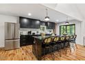Bright kitchen with black cabinets, stainless steel appliances, marble counters, and a large island with bar stool seating at 3506 Bellevue Rd, Raleigh, NC 27609