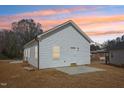 View of the home's side, featuring white siding and a concrete slab, along with manicured lawn at 608 Gilmer St, Burlington, NC 27217