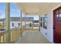 Inviting covered front porch with wood flooring, light-colored wood railings, and a view of the yard at 614 Gilmer St, Burlington, NC 27217