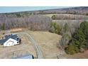 Aerial view of a home with a long driveway, surrounded by trees and a grassy area at 3344 Cobb Farm Trl, Mebane, NC 27302