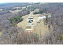 Aerial view of a property surrounded by a dense forest, featuring a house and multiple outbuildings at 3344 Cobb Farm Trl, Mebane, NC 27302