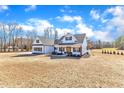 Charming white farmhouse with an inviting covered porch, neat landscaping, and spacious front lawn on a sunny day at 3608 Buzzard Rd, Wendell, NC 27591