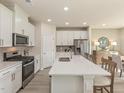 Bright kitchen features white cabinetry, stainless steel appliances, and a quartz island with seating at 3821 Rosebush Dr, Zebulon, NC 27597