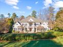 Beautiful two-story home with white exterior, a manicured lawn, and mature trees at 4708 Wynneford Way, Raleigh, NC 27614