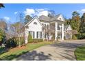 Elegant white home with a circular driveway, mature trees, and black shutters at 4708 Wynneford Way, Raleigh, NC 27614