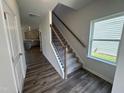 Inviting entryway featuring wood flooring, a staircase with wrought iron spindles, and natural light from a window at 60 Commons Cir, Clayton, NC 27520