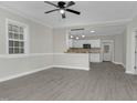 Bright living room featuring gray floors, white walls, a ceiling fan, and an open kitchen view at 915 E Holly St, Rocky Mount, NC 27801