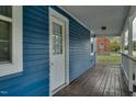 This is the side porch showing the wood plank flooring, the blue siding, and the white door at 915 E Holly St, Rocky Mount, NC 27801
