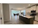 Open kitchen with a center island, granite countertops, stainless steel appliances, and white cabinets at 1013 Greatland Road, Durham, NC 27703