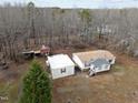 An aerial view of the property showcasing the home, storage building, and surrounding wooded area at 1469 Mollie Mooney Rd, Roxboro, NC 27574