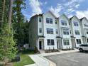 Three-story townhome featuring white siding, black windows, and a well-maintained lawn at 1551 Crescent Townes Way, Raleigh, NC 27604