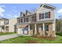 Charming two-story home featuring brick accents, gray shutters, a two-car garage and a well-manicured front lawn at 1752 Post Oak Dr, Haw River, NC 27258