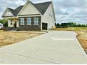 Long, concrete driveway leading to an attached garage on a new home construction with partially sodded yard at 190 Sage Ln # 015, Four Oaks, NC 27524