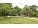 Quaint single-story brick home with a well feature, surrounded by lush green trees and a spacious lawn at 2409 Parkway Dr, Raleigh, NC 27603