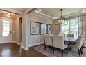 Dining room featuring hardwood floors, a modern chandelier, and large windows with custom curtains at 840 Emerald Bay Cir, Raleigh, NC 27610