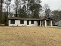 Renovated brick house with black shutters and covered entrance, surrounded by mature trees and natural landscaping at 905 Spruce Pine Trl, Durham, NC 27705