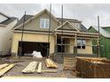 New construction home in progress showcasing its architectural details with open garage and unfinished siding at 104 Bearwallow Forest Way, Wendell, NC 27591