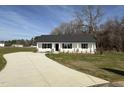 Charming single-story home with a white exterior, black shutters, and a long concrete driveway at 107 Faucette Dr, Selma, NC 27576