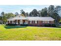 Charming brick home featuring a cozy front porch, mature landscaping, and classic architectural details at 4409 Driftwood Dr, Raleigh, NC 27606